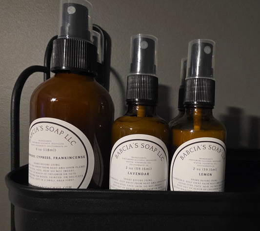 Three bottles of Babcia's Soap LLC products on a dark surface with a gray background.