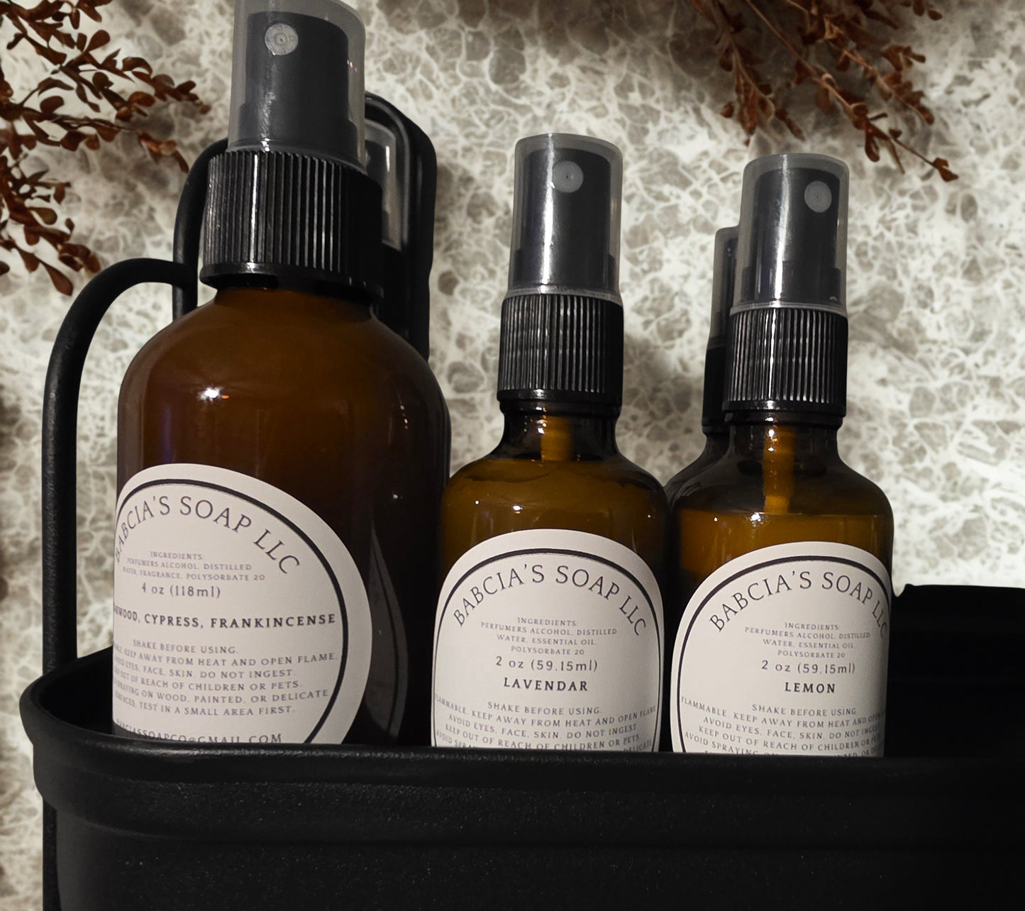 Set of three brown bottles with black sprayers and labels on a textured surface.