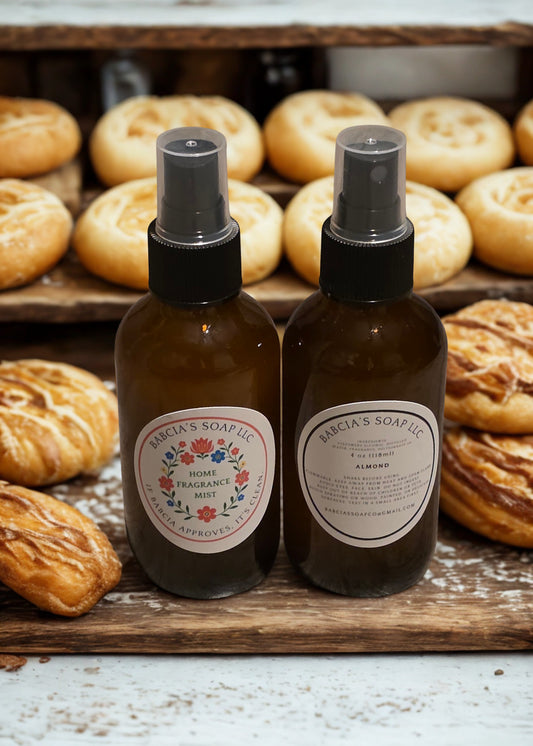 Two brown spray bottles with labels on a wooden surface with pastries in the background