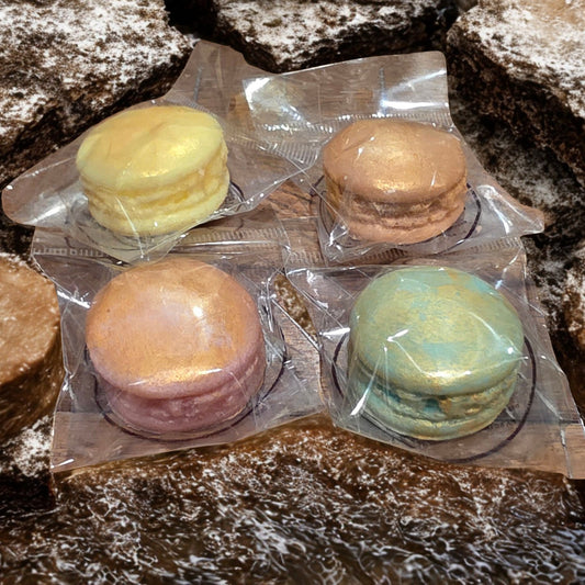 Four macarons in clear packaging on a stone surface